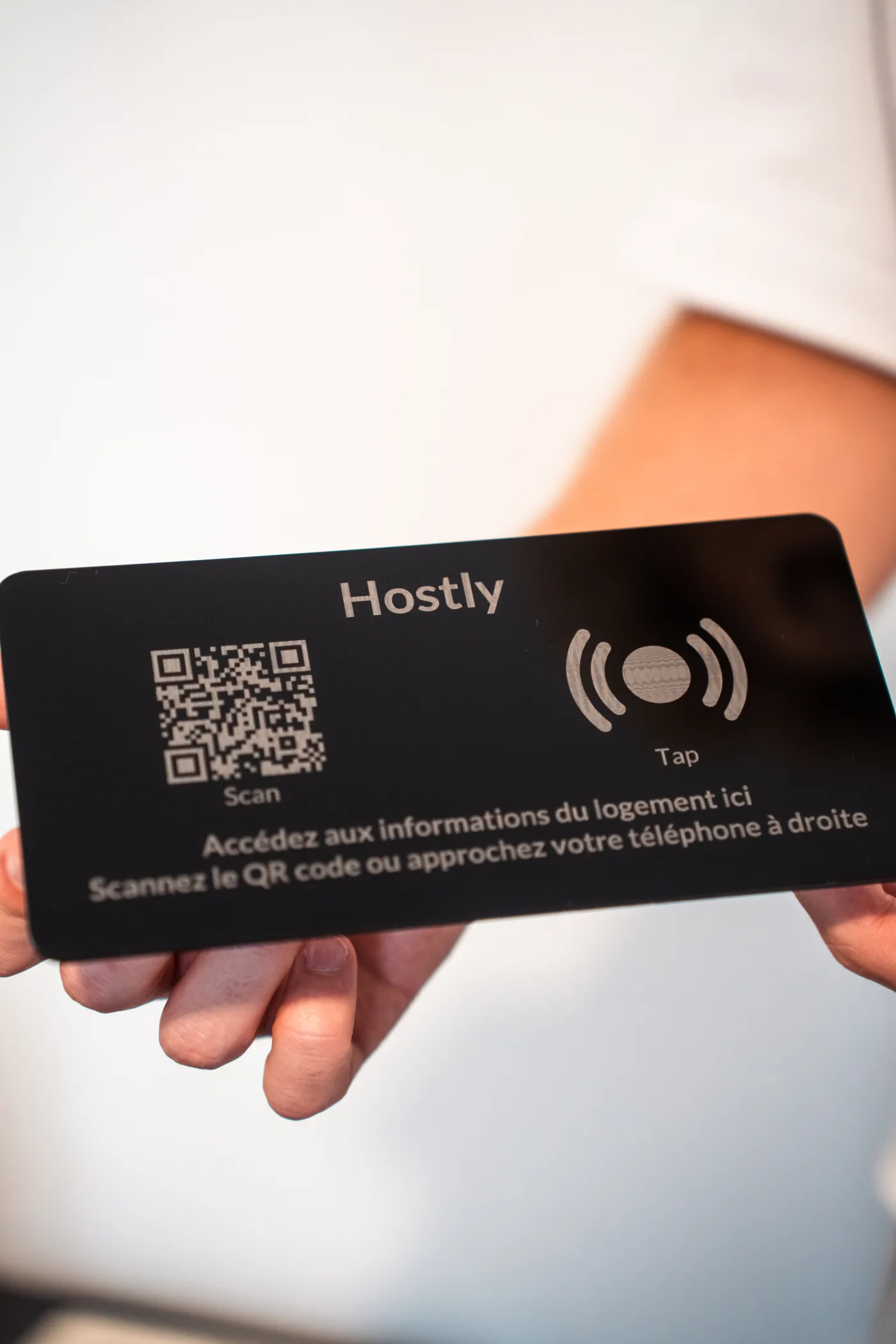 Totem Hostly plexi noir tenu en main, gros plan
