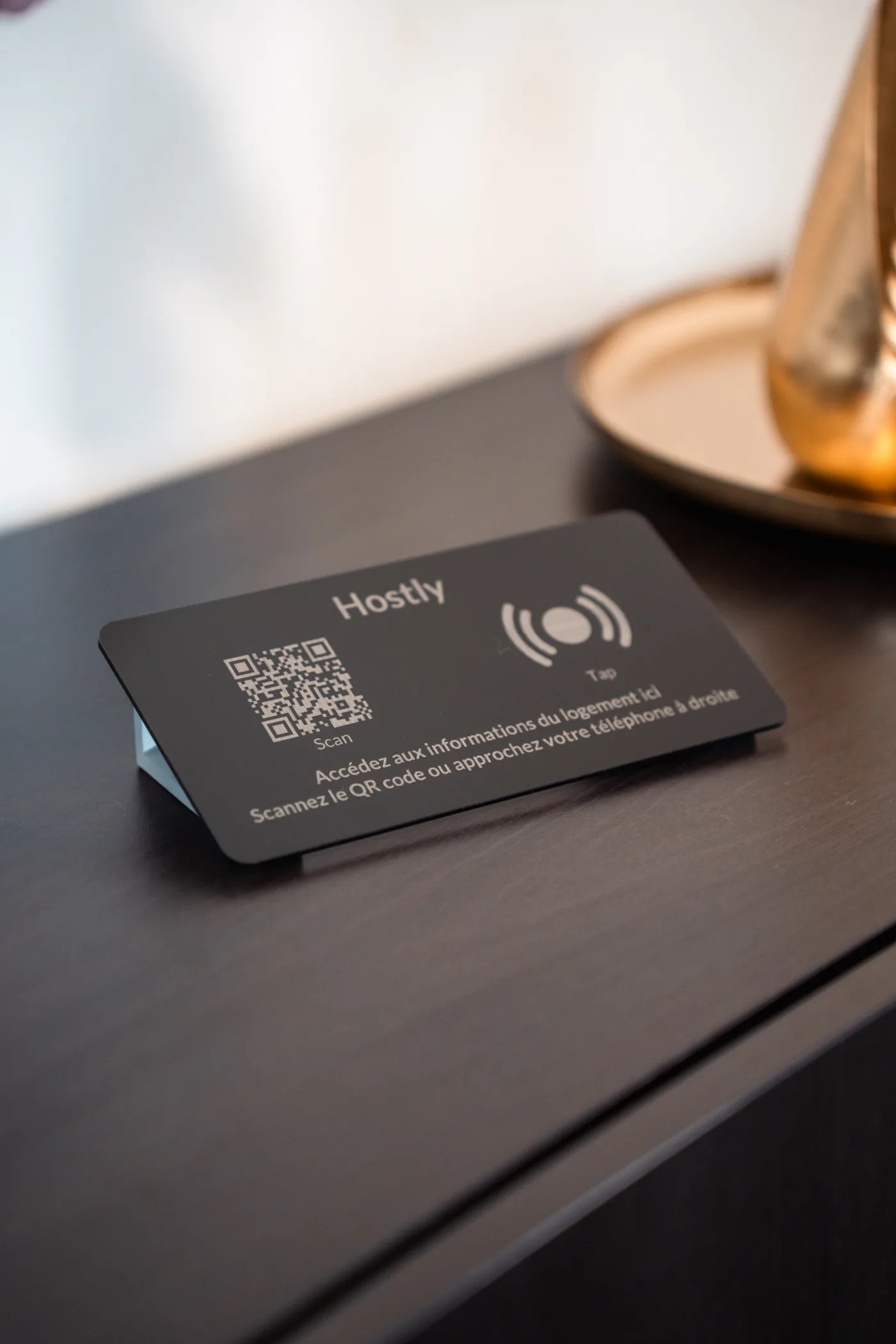 Totem Hostly plexi noir sur table sombre avec décoration dorée